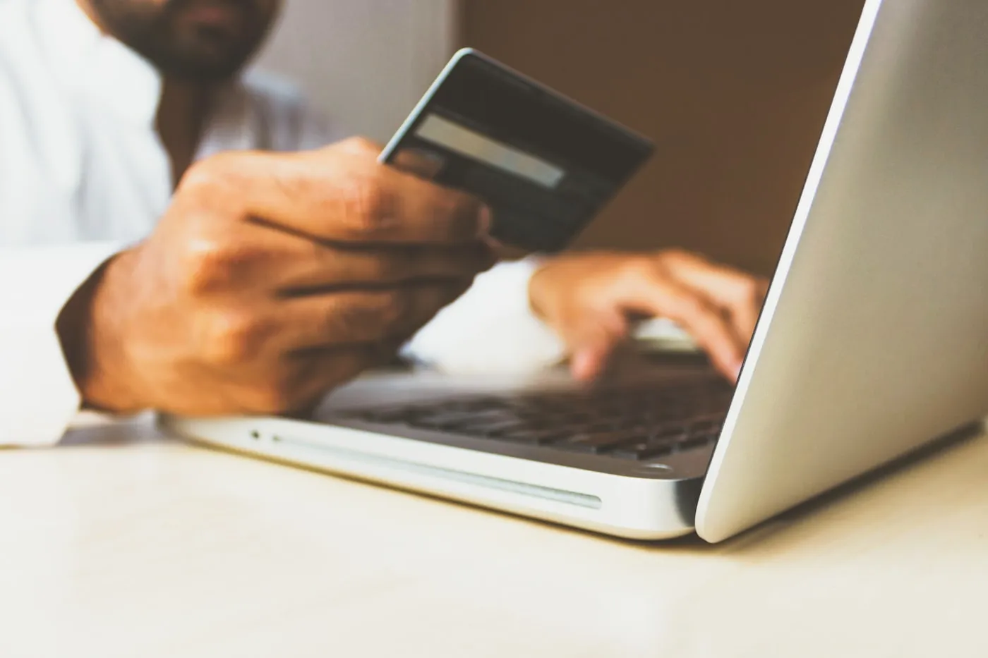 Persona comprando en línea con tarjeta frente a una laptop
